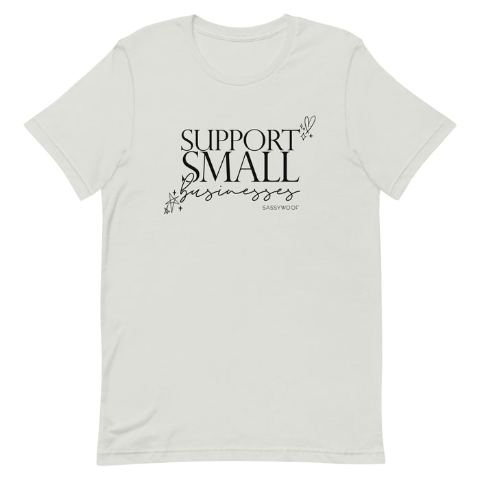 The Support Small Businesses Tee by Sassy Woof is an eco-friendly unisex shirt with black “SUPPORT SMALL businesses” text in mixed fonts, star and heart doodles, and “Sassy Woof” printed subtly below.