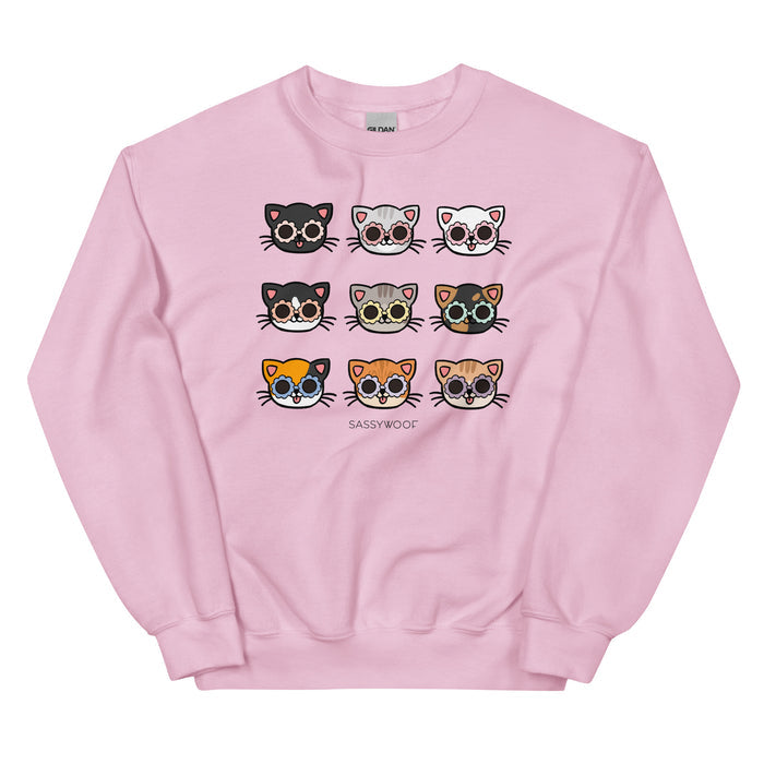 The Sassy Woof Sweatshirt - Cats is a pink unisex crewneck featuring a white "SASSYWOOF" print and nine unique cartoon cat faces, making it a cozy addition to any cat lover’s wardrobe.