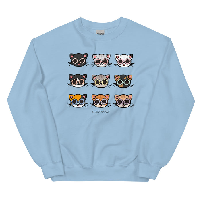 The Sassy Woof Sweatshirt - Cats is a light blue top with a 3x3 grid of colorful cat faces above "SASSY WOOF" in bold text—a comfy pick for any feline fan.