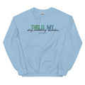 The Sassy Woof "This is My Dog Cuddling Sweater" is a light blue unisex crewneck sweatshirt featuring the phrase in green, blue, and black fonts on the front.
