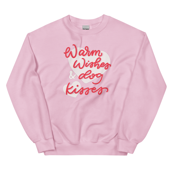 The Sassy Woof "Warm Wishes & Dog Kisses" sweatshirt features soft, light pink fabric with the phrase in playful red and white script across the front.
