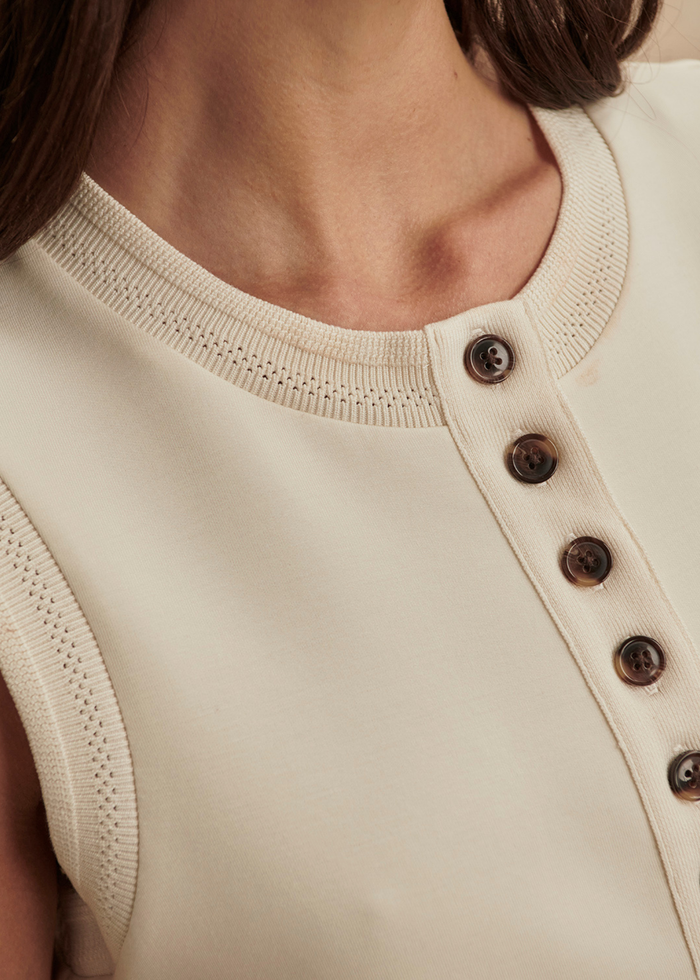 Close up of a woman wearing an ivory button tank top with matching shorts