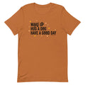 The Sassy Woof Wake Up, Hug A Dog, Have A Good Day Tee is an orange unisex 100% cotton shirt featuring bold black text and yellow and white star designs—a comfy tee perfect for dog lovers.
